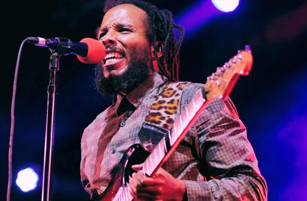 Ziggy Marley Drops Unreleased Demo Via Charity NFT Collection image of reggae musician Ziggy Marley performing guitar and singing during a live concert